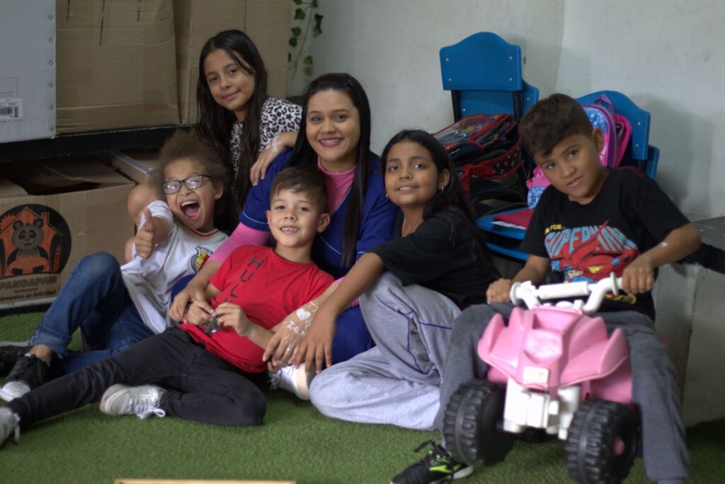 Andrea, a teacher at Casa de Sueños, with a few of her students, laughing.