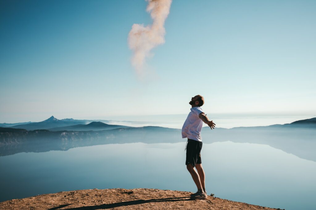 man lifting head to the sky while walking the beach