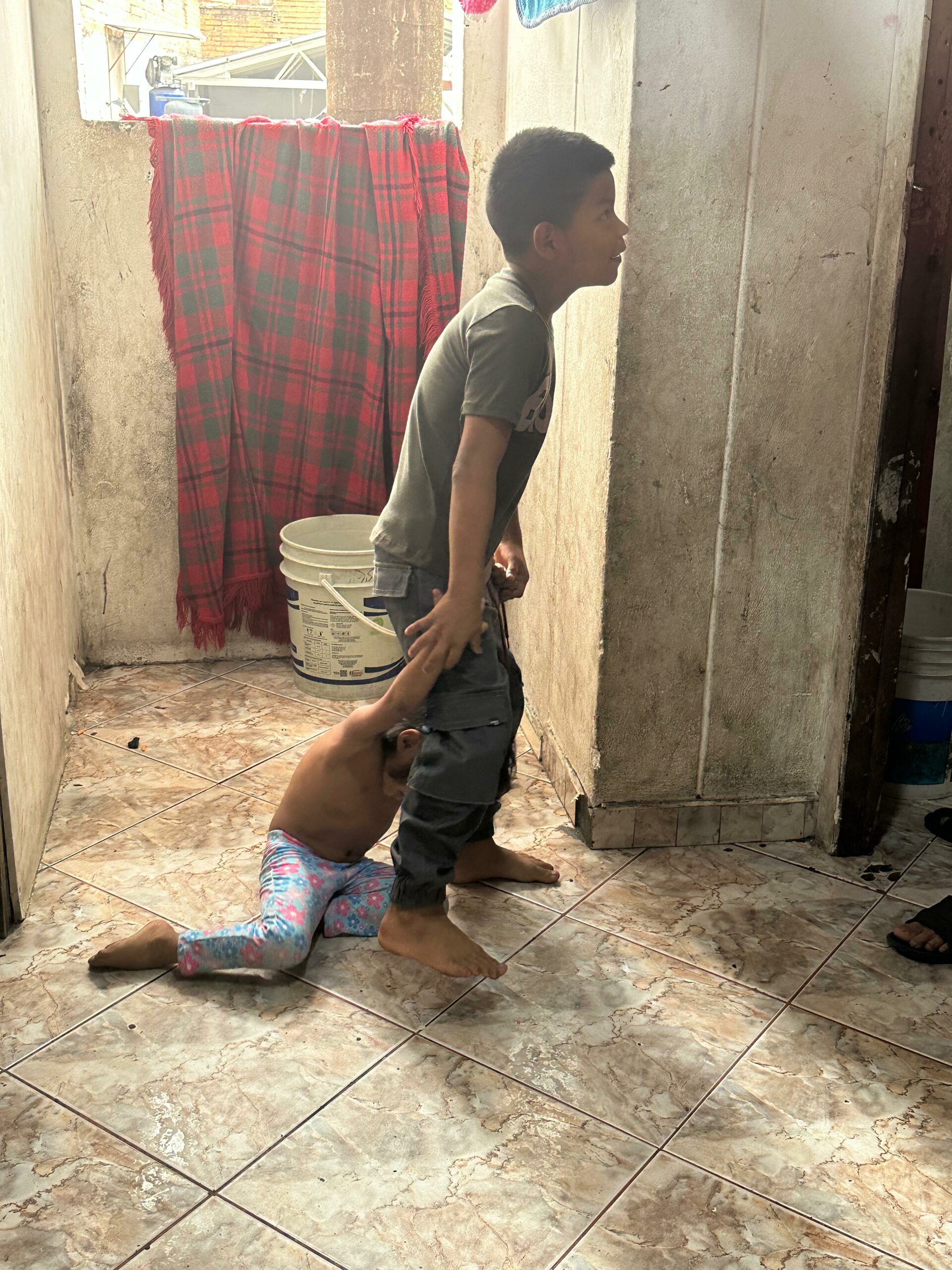 Young boy dragging toddler brother in Medellin's inquilinatos.