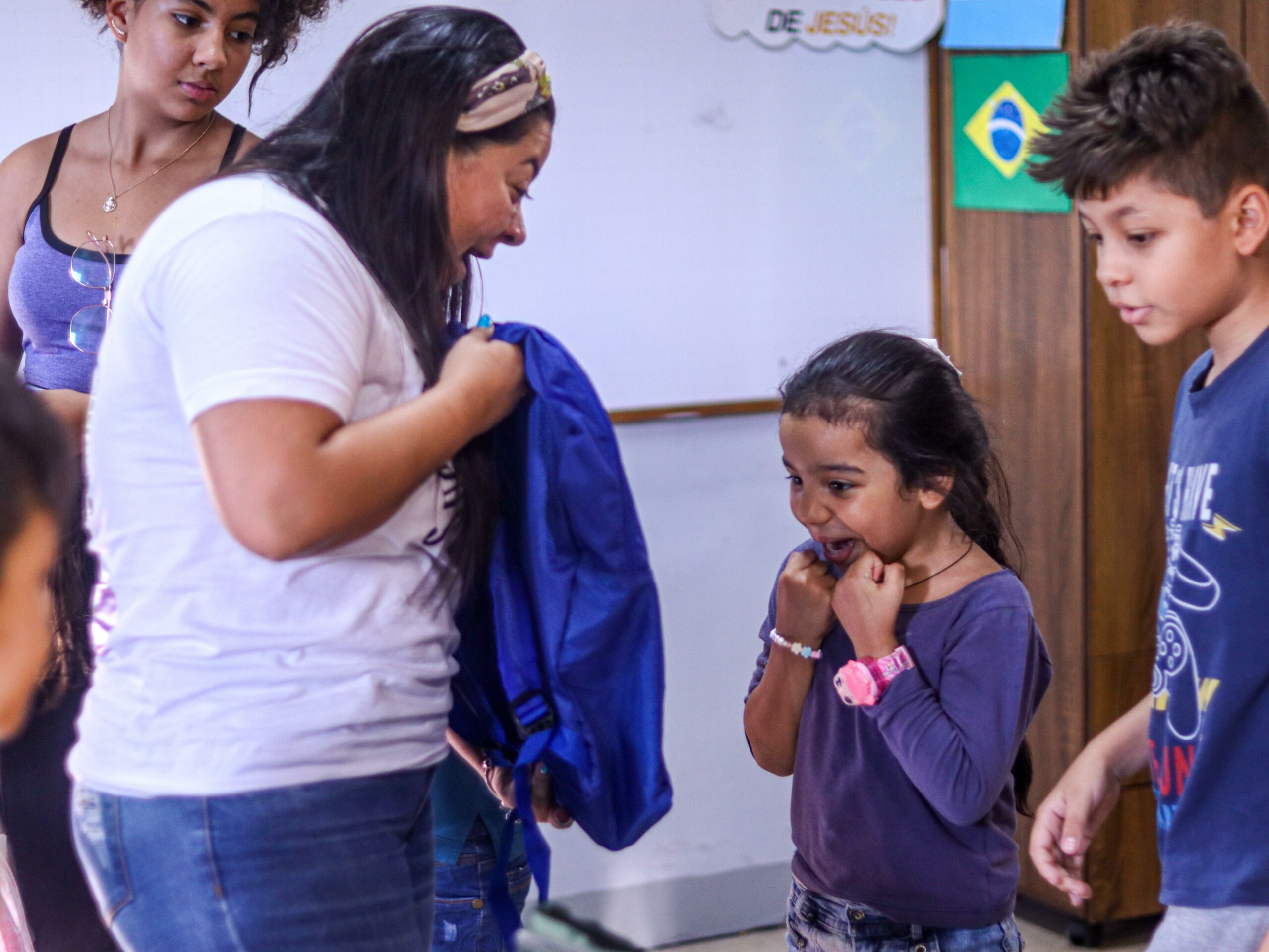 A girl from Medellin's inquilinatos gleefully receiving the simple gift of a backpack from Casa de Sueños