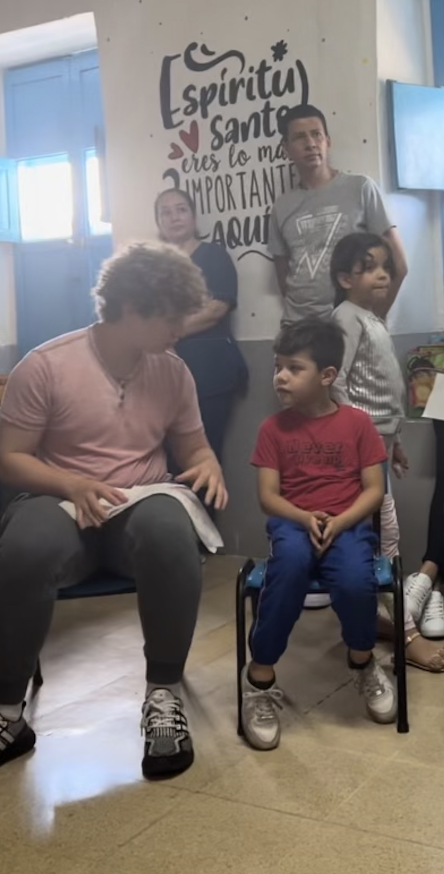 Alec de voluntario en Casa de Sueños, enseñando a un niño pequeño.