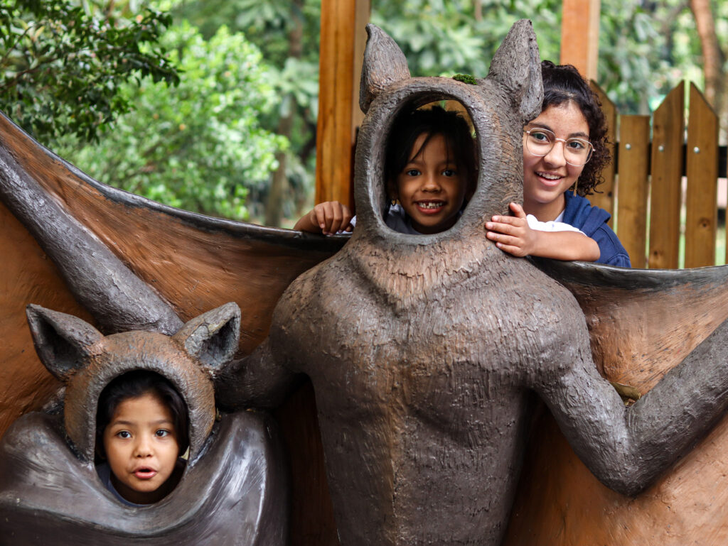 3 gi4ls from Casa de Sueños pose in animal statues at the Medellin zoo.