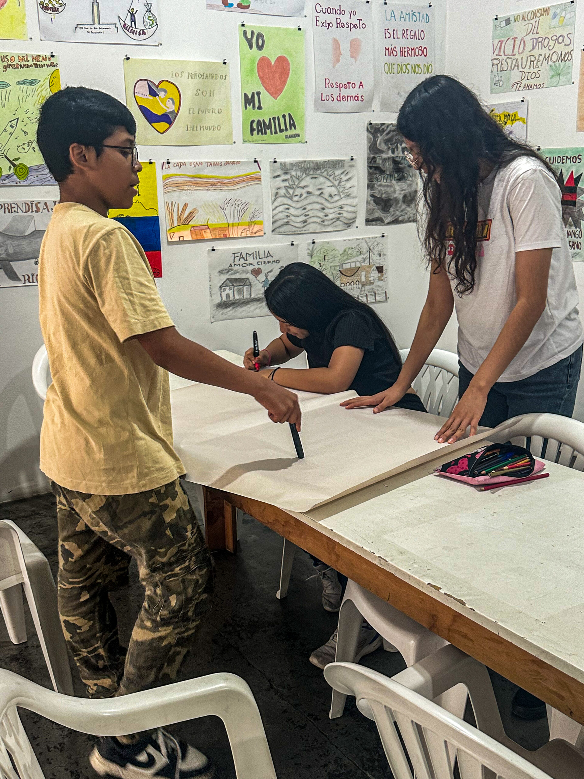 Teenaged boy discussing project with friends in New Generation teen program at Casa de Suenos. 